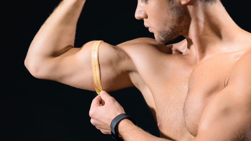 Hombre se mide los músculos del brazo con un metro y hace alusión a la vigorexia