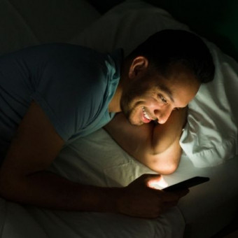 Hombre revisa su celular antes de dormir