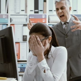 Mujer con las manos en el rostro tras ser gritada por su jefe en un acoso laboral